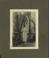 Woman in white dress, holding onto a parasol, looking to her right