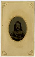 Portrait of little girl with bow on top of her head, framed by mat