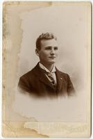 Portrait of a young man with no facial hair and a pin on his textured tie