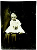 Photo of an infant with blushed cheeks in a white dress
