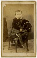 Portrait of an infant with long boots on a tassled chair