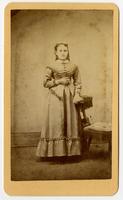 Photo a standing woman with pulled back curls and a choker. Posing with tassled chair