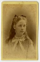 Portrait of a young woman with a striped top, black hairbow, and dangling earrings