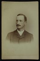 Portrait of a young man with a trim dark mustache