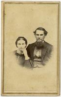 Portrait of a woman with a hairbow resting her hand on her chin and a bearded man with blushed cheeks