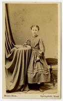 Photo of a young girl with dotted dress, book on side table