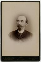 Portrait of a balding man with a mustache and a small beard