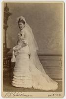 Photo of a standing woman in a wedding dress and long veil