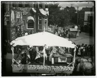 Covered parade float with a cow banner on a desk (Semi-Centennial Parade)