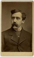 portrait of man with mustache and rectangular metal pendant