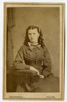 Portrait of a woman with her curled hair down, wearing a choker and a bow