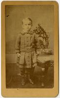 Photo of an infant standing with an ornate chair
