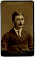 Portrait of a man with a mustache, sideburns, tie, and textured jacket