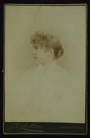 Profile portrait of a young girl with a braided bun and curly bangs