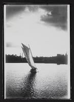 Sailboat on river with town in background