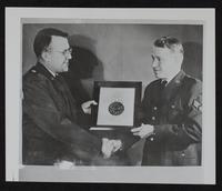 Air Force Sgt. Charles (Bob) Henderson of Lawrence honored with plaque from Maj. Gilbert H. Bertie.