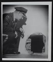 Patrolman Roy Bledsoe inspects hole made by burglars.