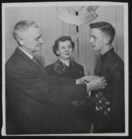 Andy Graham, of 1740 Indiana Street receiving Eagle Scout Insignia from Max Richardson, assistant scoutmaster. Mother Mrs. C. A. Graham looks on.