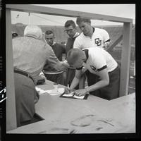Athlete signing something (registration?) at a table