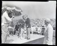 Woman holding a bouquet and standing next to a young man on a stage in the track field