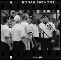 Group of men wearing striped shirts with SOX on the left side stand at microphones