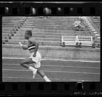 Athlete with three horizontal stripes on his tank top running a relay race