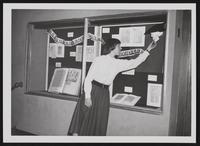 Library staff member arranging display case exhibit